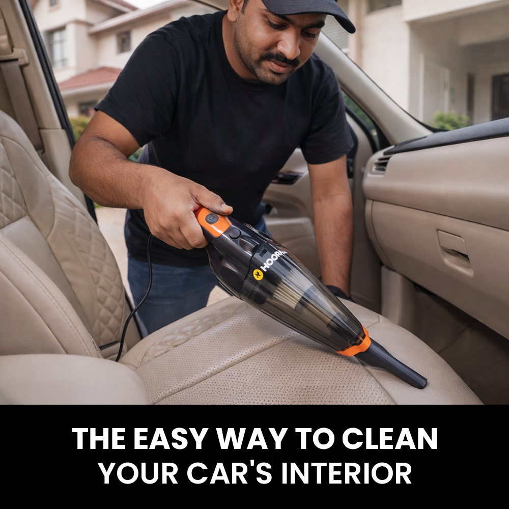 Man cleaning a car's interior with a handheld vaccum cleaner.